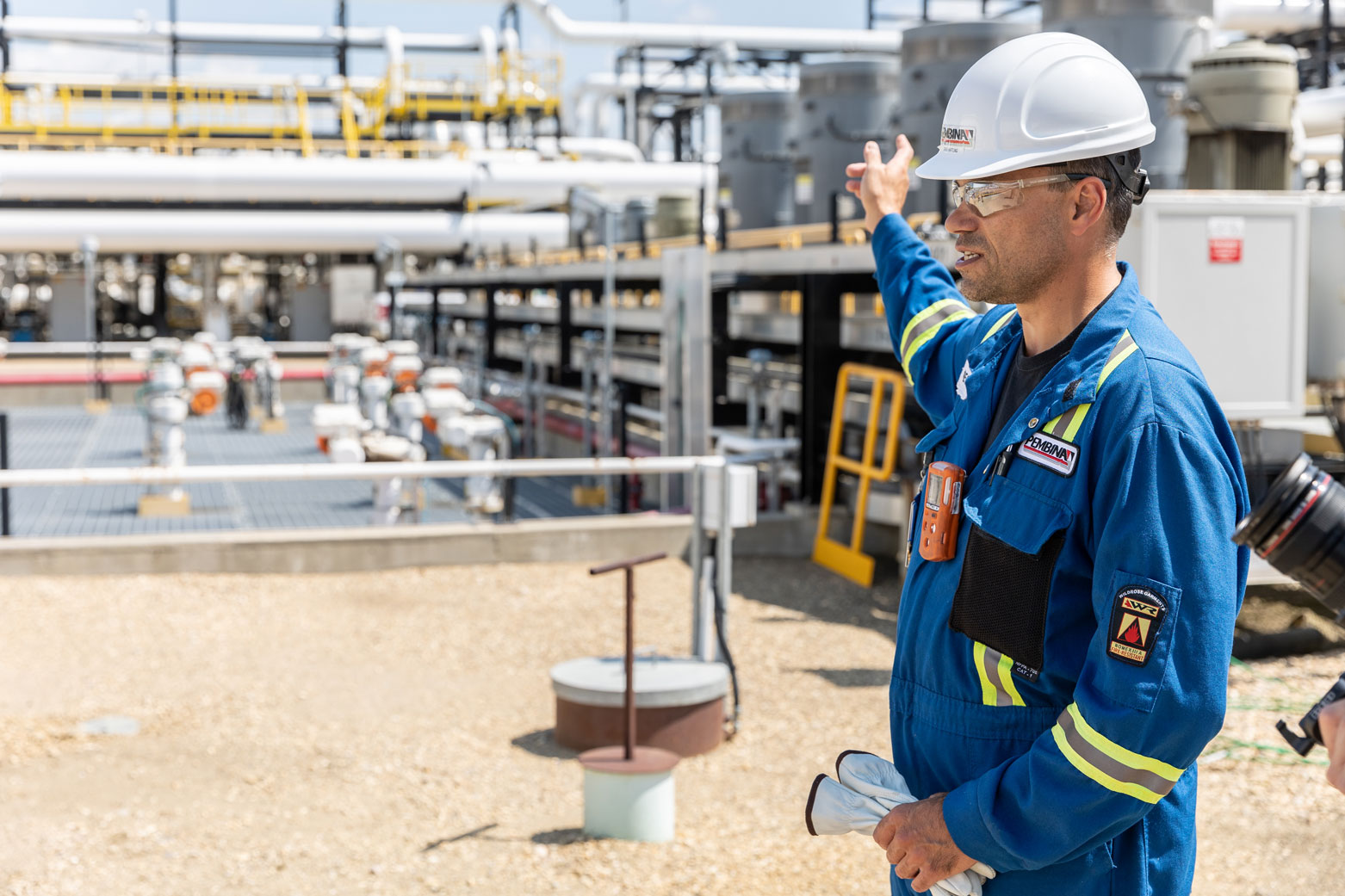 A refinery supervisor points toward processing piping and equipment.