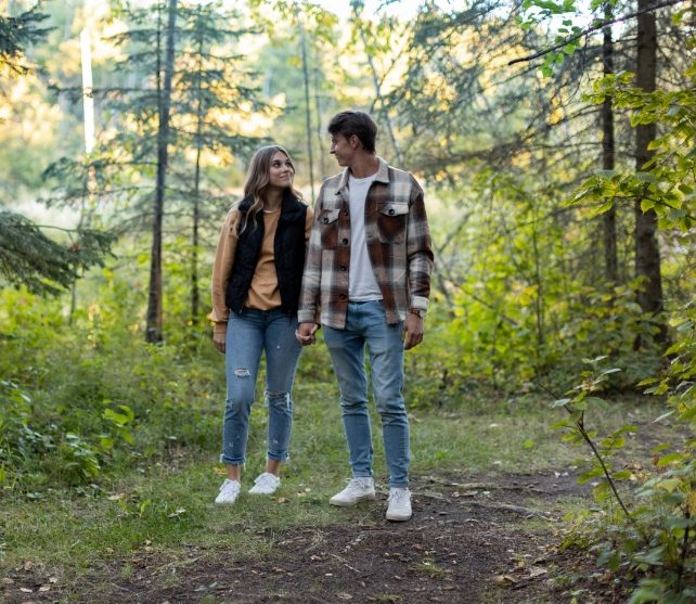 A couple walks together on a trail through the woods.