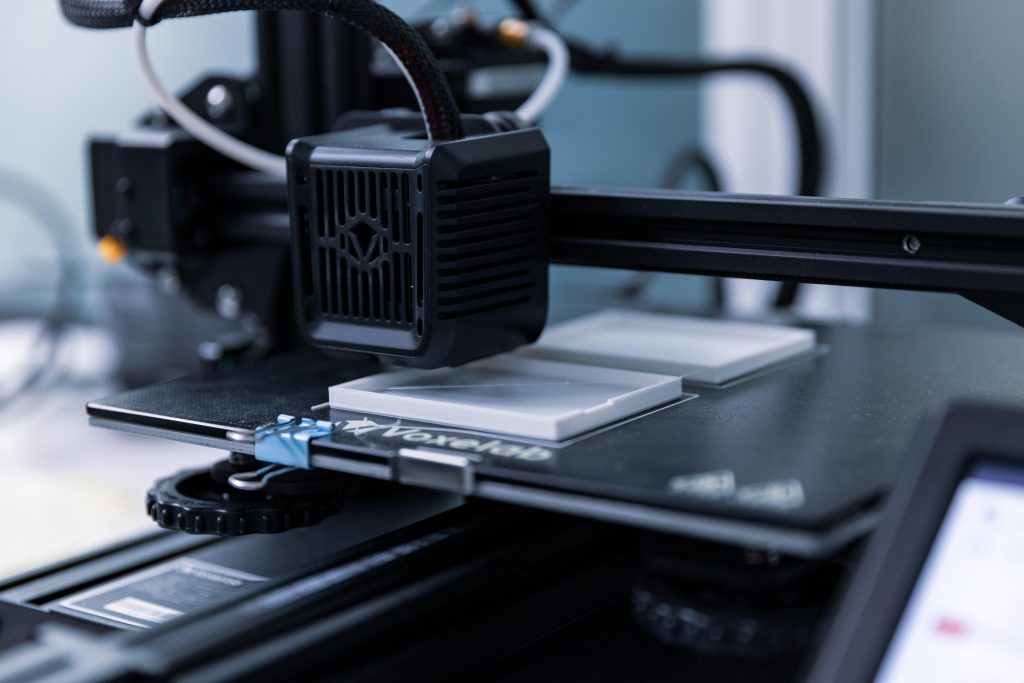 A 3D printer constructs plastic components.