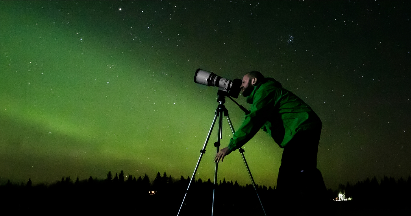 A man looks through the viewfinder of a camera, capturing astronomical photos.